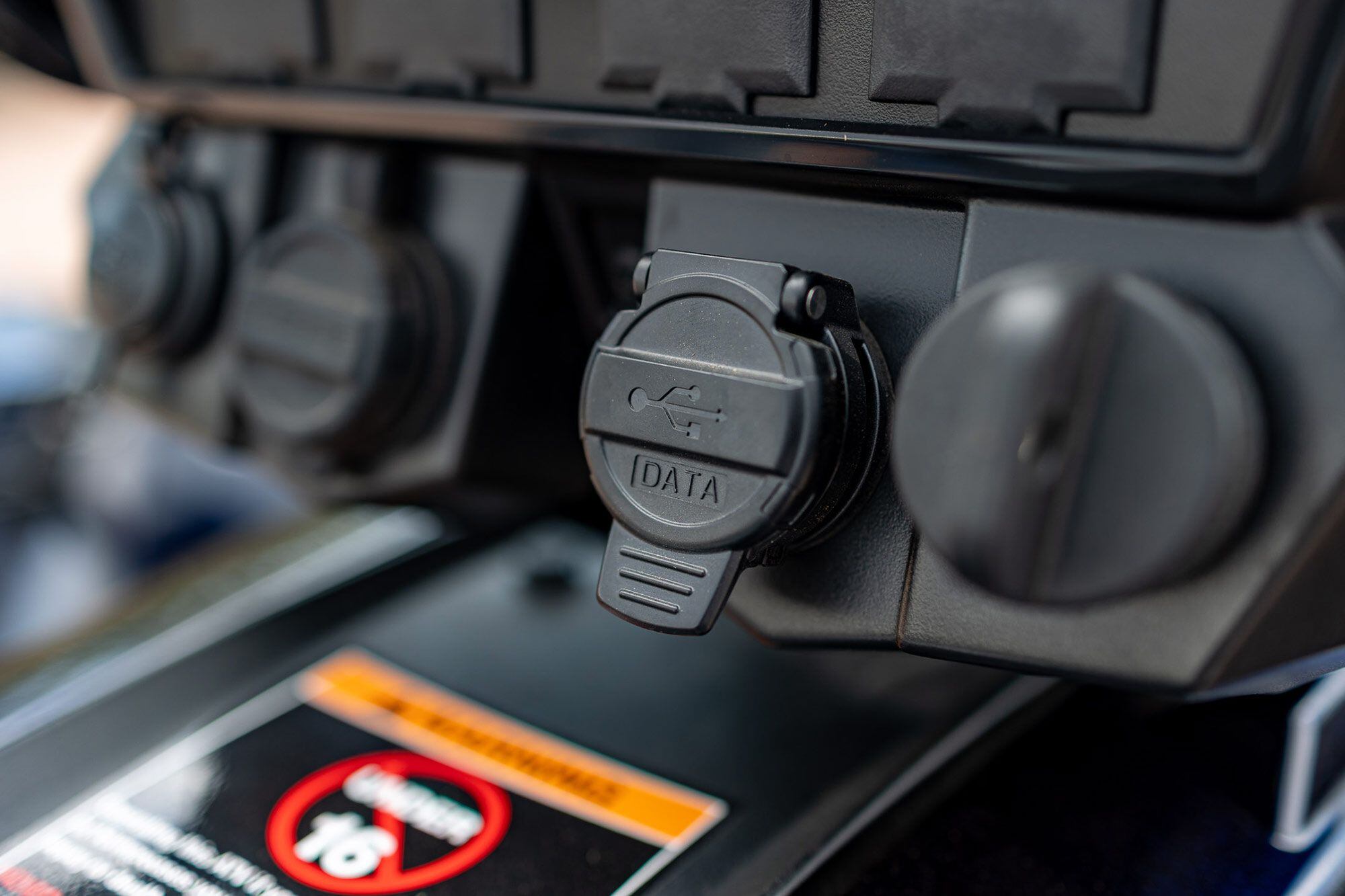 A 12-volt power socket, battery charger connector, and data port can be accessed below the Ride Command display.